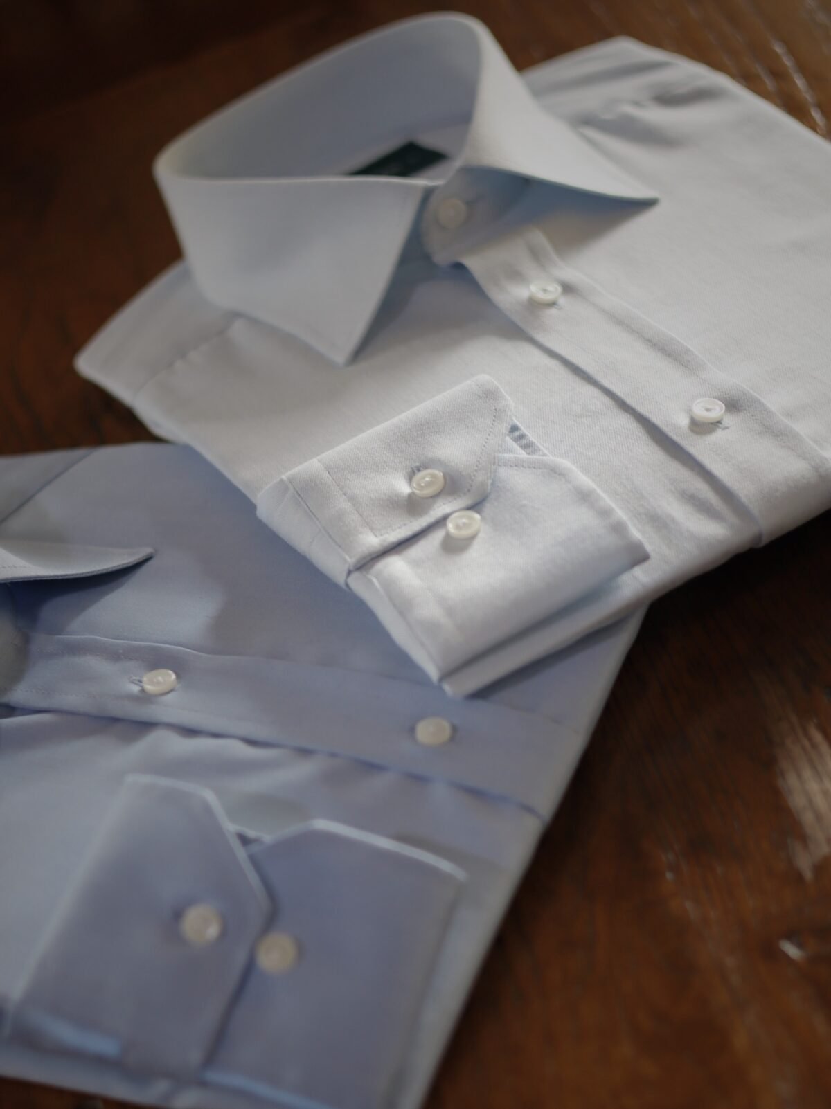Camisas formales blanca y azul cielo dobladas sobre madera