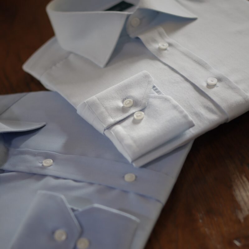 Camisas formales blanca y azul cielo dobladas sobre madera